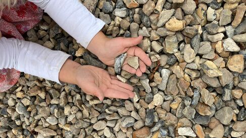 child with hands holding pieces of gravel