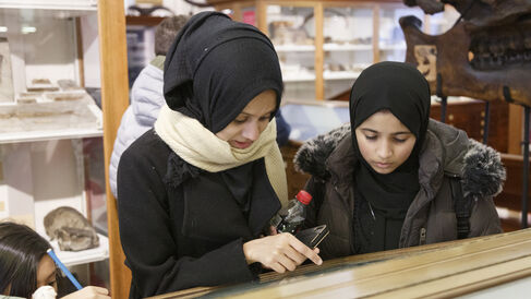 two women in black head scarf looking in a museum case